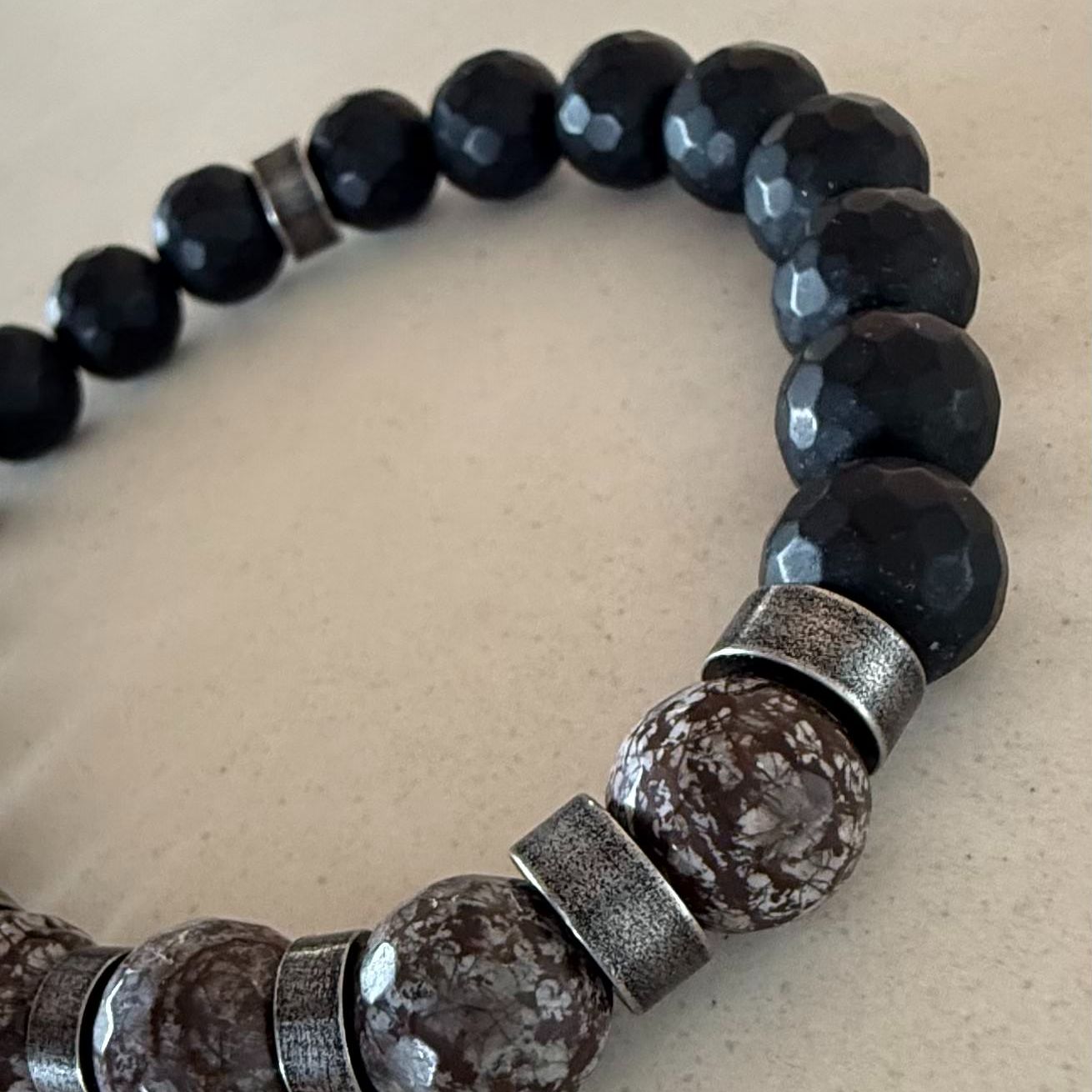 Bracelet with black and brown beads on a beige background