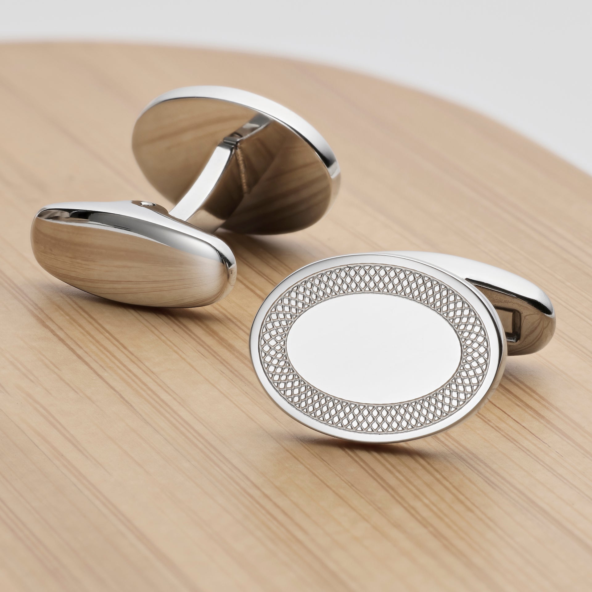A pair of oval silver-toned Oval Frame Cufflinkscan be engraved. One cufflink is shown from the back with a brushed metallic finish, and the other is shown from the side, featuring a polished silver border with a textured inner ring and a blank white oval center.