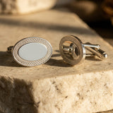A pair of oval silver cufflinks with engraved geometric borders.