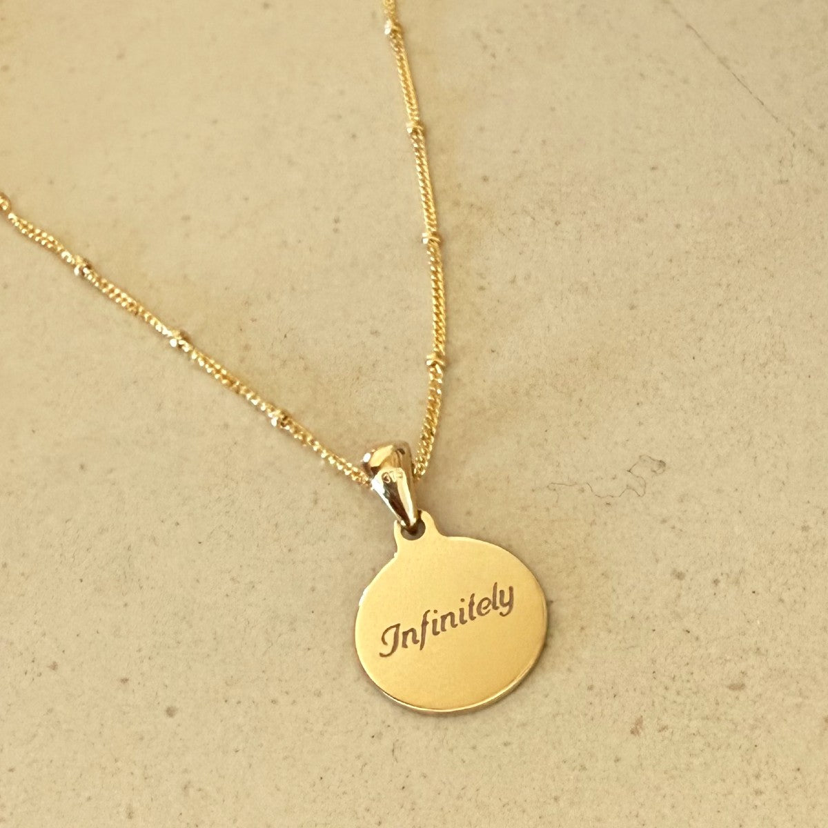 9ct gold disc engraved with infinitely paired with a 9ct gold satellite chain 