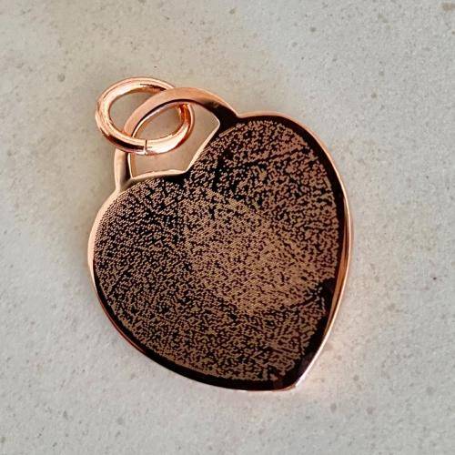 two overlapping fingerprints engraved onto a heart pendant