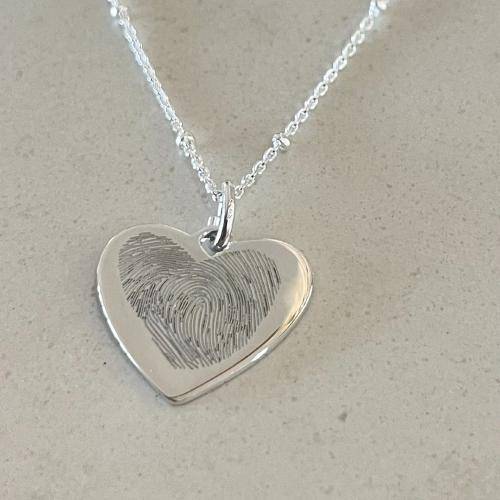 two-fingerprint-engraved-in-a-heart-shape-on-a-silver-necklace-